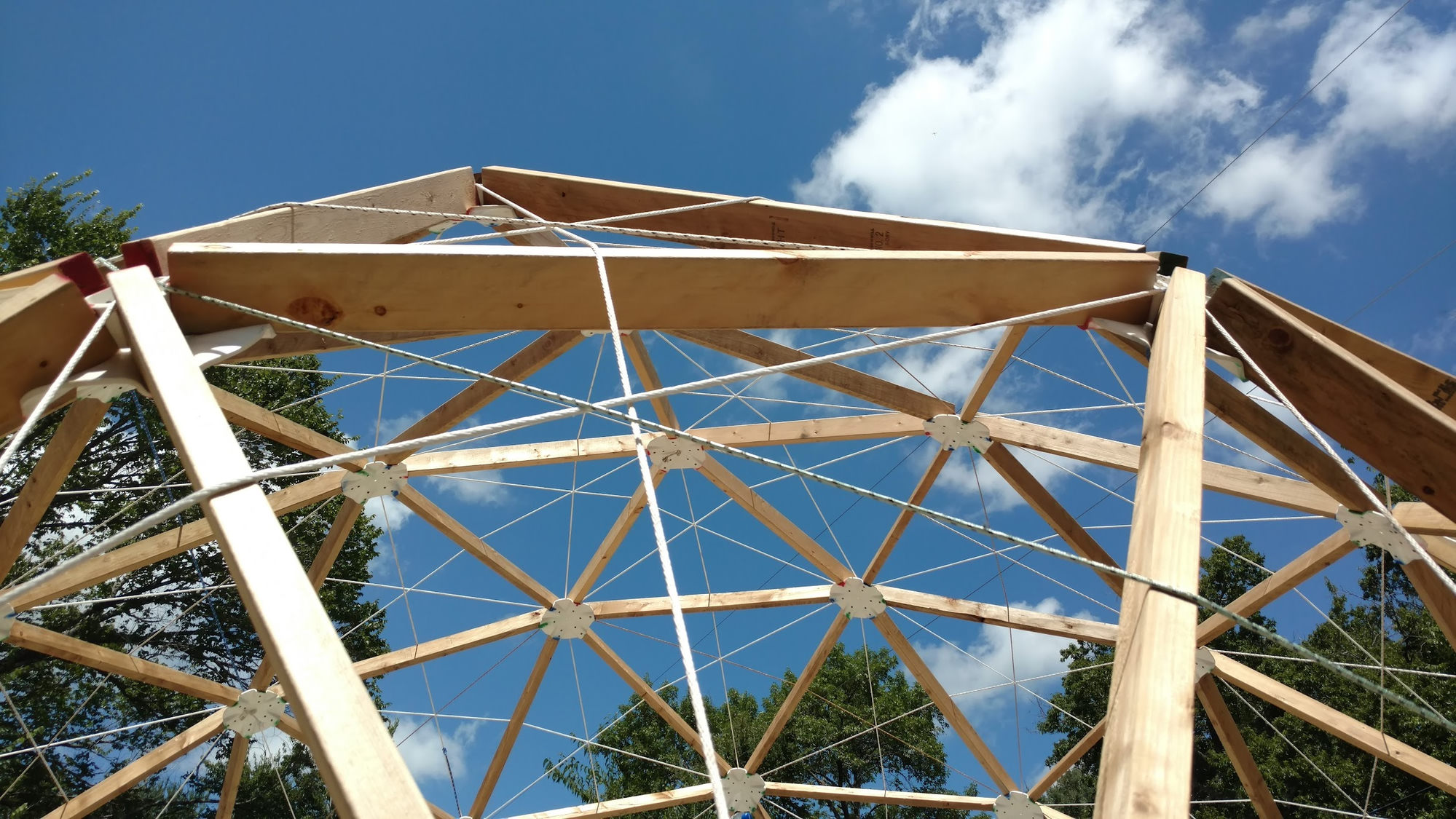 Looking up through the proof dome's 2x4 frame at a blue Texas sky, white hubs at every joint